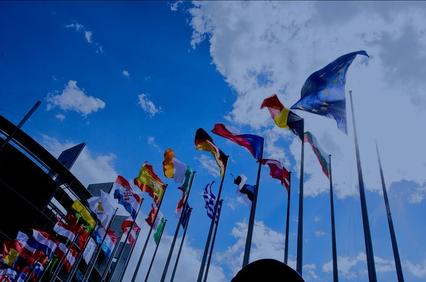 A display of various flags waving under a bright blue sky.