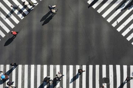 Aerial view of pedestrians crossing a large zebra crossing in an urban setting.
