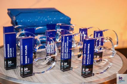 A display of awards on a circular table with a blue package in the background.