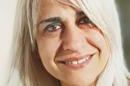 A woman with long blond hair is smiling at the camera.