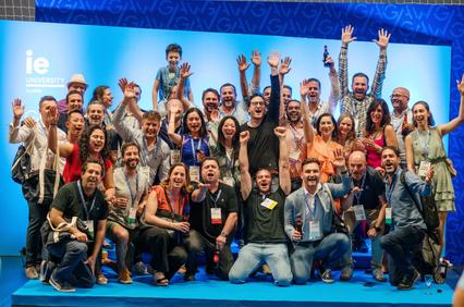 A vibrant group of people celebrating together with raised hands and smiles at an event.