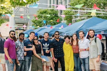 A group of friends posing together at an outdoor event with colorful decorations.