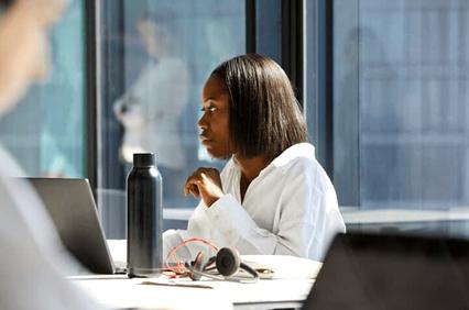 A focused woman working on a laptop in a modern office setting.