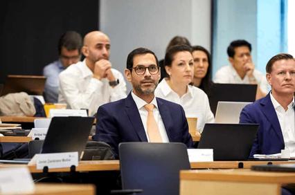 A group of professionals sitting at a conference table focusing on a presentation.