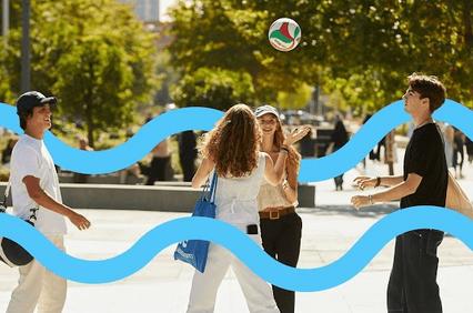 A group of friends playing volleyball outdoors in a sunny setting.