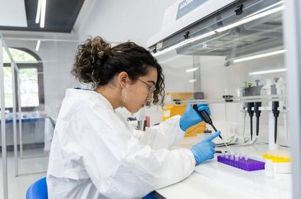 A scientist is carefully using a pipette in a laboratory setting.
