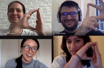 Four people smiling on a video call, making heart shapes with their hands.