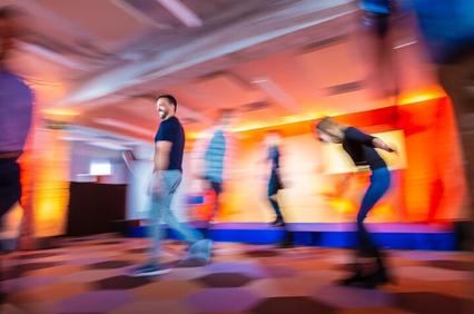 A dynamic scene capturing people moving in a vibrant, blurred environment.