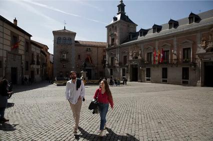 A couple is walking through a cobblestone plaza surrounded by historical buildings.