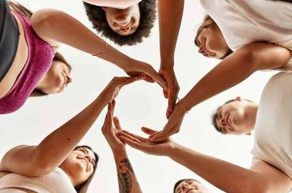 A diverse group of people joining their hands in a circle from a low angle perspective.