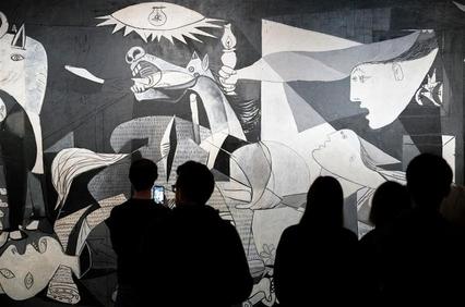 A group of people observing a striking black and white artwork featuring distorted figures and chaotic elements.