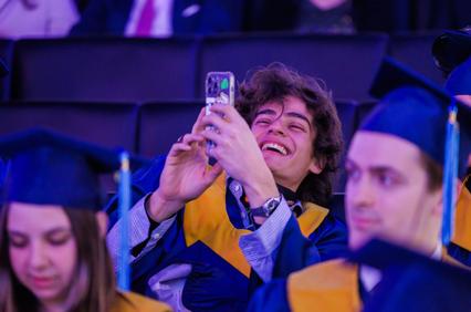 A happy graduate taking a selfie at a graduation ceremony.
