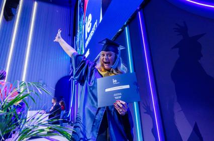 A graduate celebrating with a diploma at a graduation ceremony.