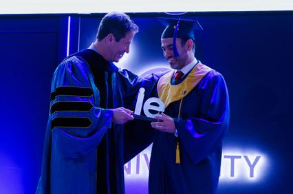 A graduate receiving a diploma from a faculty member during a ceremony.