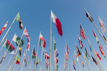 A vibrant display of national flags against a clear blue sky.
