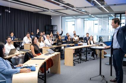 A group of people is engaged in a classroom setting with a speaker addressing them.