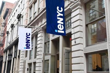A street view of a building with flags displaying the logo of 'ieNYC'.