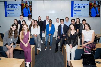 A group of diverse individuals posing for a photo in a classroom setting with posters about leveraging LinkedIn in the background.