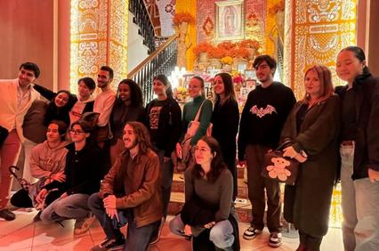 A group of people posing together in a richly decorated interior space with ornate gold designs.