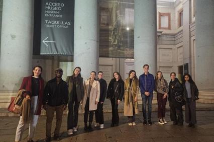 A group of diverse young adults standing in front of a museum entrance at night.