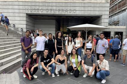 A group of people posing in front of the Museo del Prado entrance.