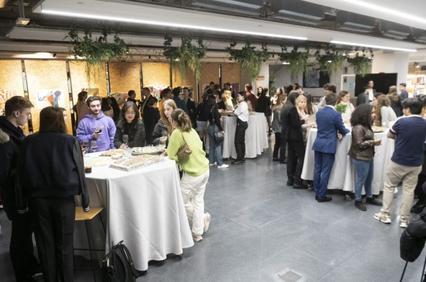 A group of people gathered at an indoor event, possibly a networking event, with tables of food and beverages.