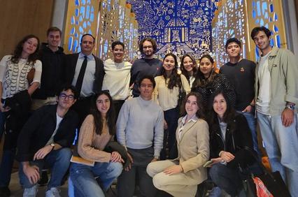 A group of young adults posing for a photo indoors with a blue decorative backdrop.