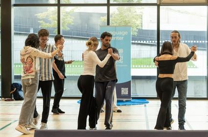 Adults practicing dance moves in a group workshop inside a modern building.
