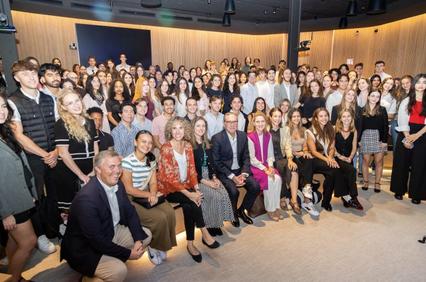 A large group of diverse people posing for a photo in a seminar room.