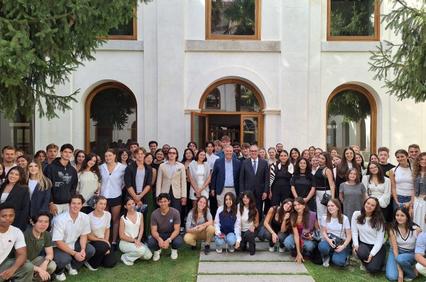 A large group of students posing in front of a building with two adults, likely at a school or university event.