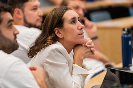 A woman attentively listens during a lecture, showing deep thought.
