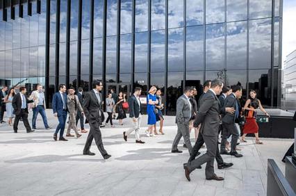A group of business professionals walking outside a modern office building.