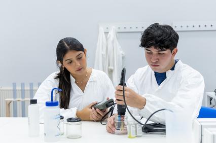 Two young individuals in laboratory coats are engaged in a scientific experiment at a laboratory table.