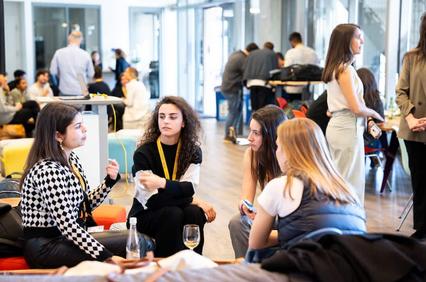 A group of women engaged in a conversation at a networking event inside a modern office space.
