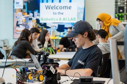A group of students are engaged in robotics and AI projects in a modern lab setting.
