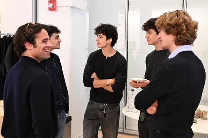 A group of five young men engaging in a casual conversation indoors.