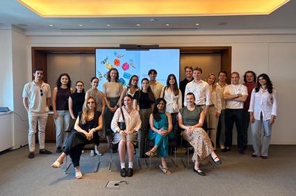 A diverse group of people poses for a photo in a modern room decorated with colorful artwork.