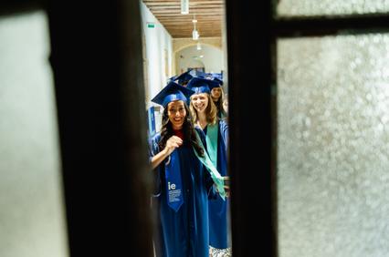 A group of smiling graduates in caps and gowns celebrating their graduation.