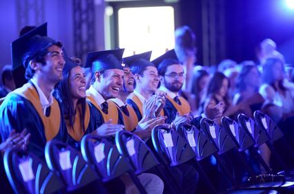 A group of happy graduates celebrating at a commencement ceremony.