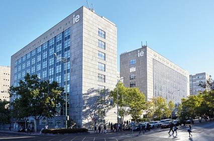 A modern university campus with glass buildings and trees in a clear blue sky.