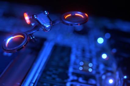 A small drone illuminated by blue and red lights hovering above a circuit board.