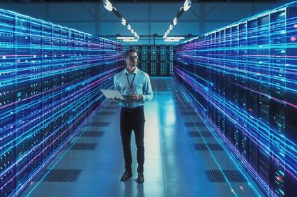 A technician working in a modern data center filled with glowing server racks.