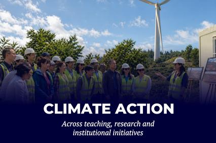 A group of people in safety gear engaging in a climate action discussion near a wind turbine.