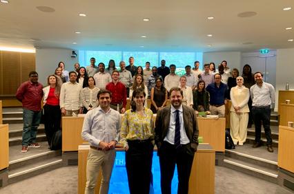 A diverse group of people poses together in a seminar room.