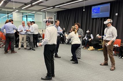 A group of people is engaged in a virtual reality experience in a modern office setting.