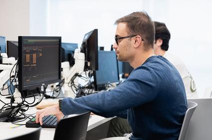 A person sitting at a computer desk working on a project.