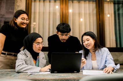 A group of young professionals collaborating around a laptop in a cozy workspace.