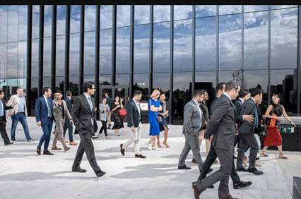 A diverse group of professionals walking in front of a modern building on a sunny day.