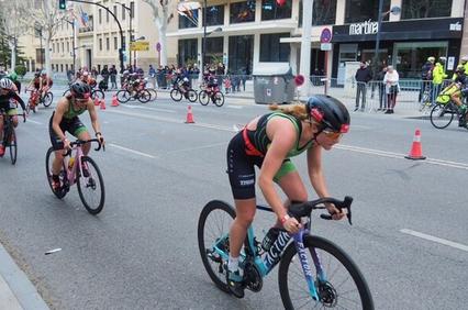 Female athletes competing in a cycling race on an urban road.