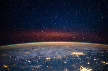 A stunning view of Earth from space, showcasing its curvature and illuminated cities against a starry backdrop.